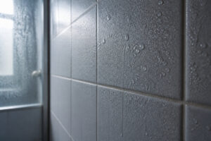 Gros plan sur un mur de salle de bain carrelé couvert de condensation et de gouttes d'eau après une douche.